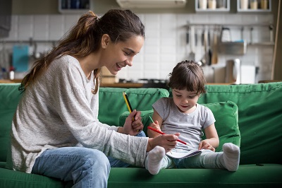 Mom and kid girl drawing with colored pencils at home